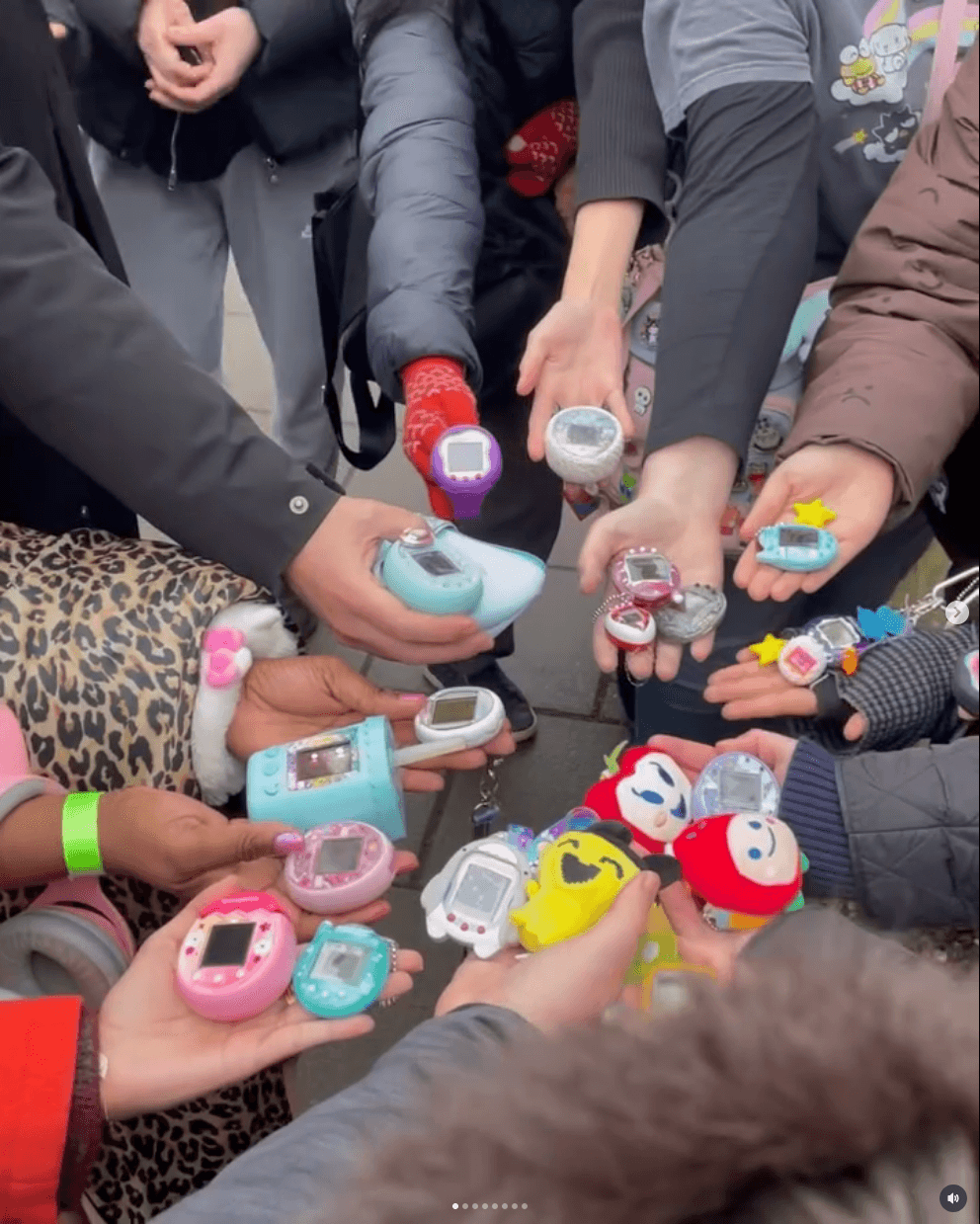Many people in a circle holding Tamagotchis